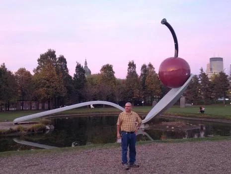 a man standing in front of a giant spoon, trees of mn